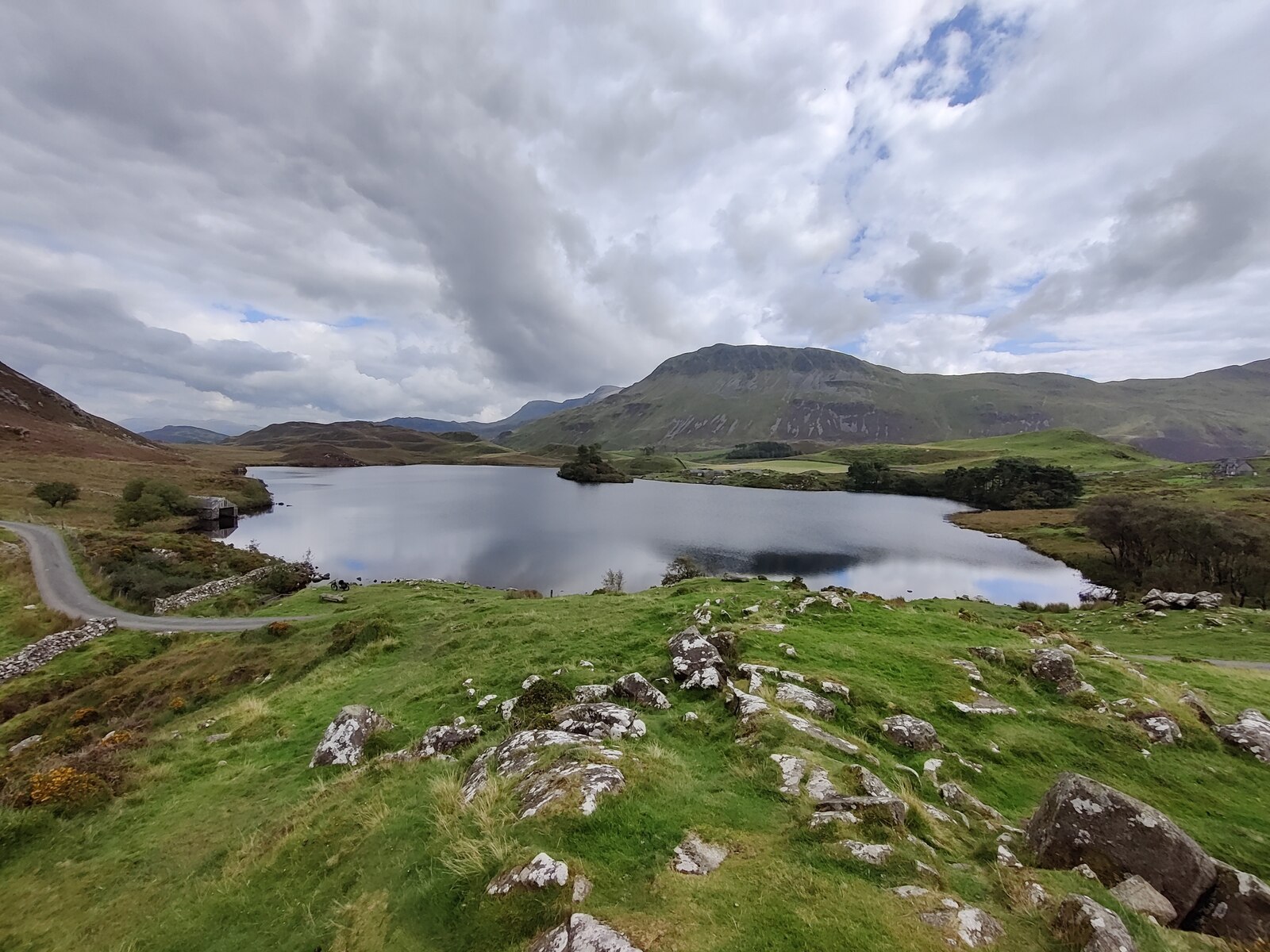 Llynnau Cregennan lakes beneath the Cadair Idris massif in Gwynedd, North Wales, under a heavy gray sky.