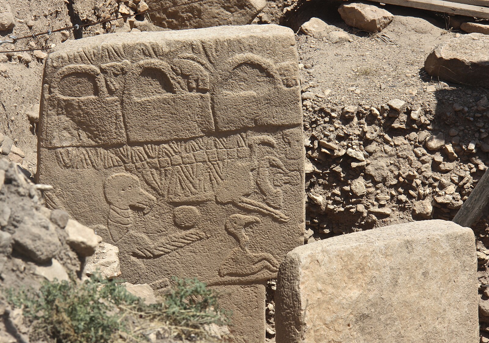 The Vulture Stone, Pillar 43 at Göbekli Tepe, a carved limestone pillar with vulture, scorpion, and bag-shaped reliefs, standing in the excavation.