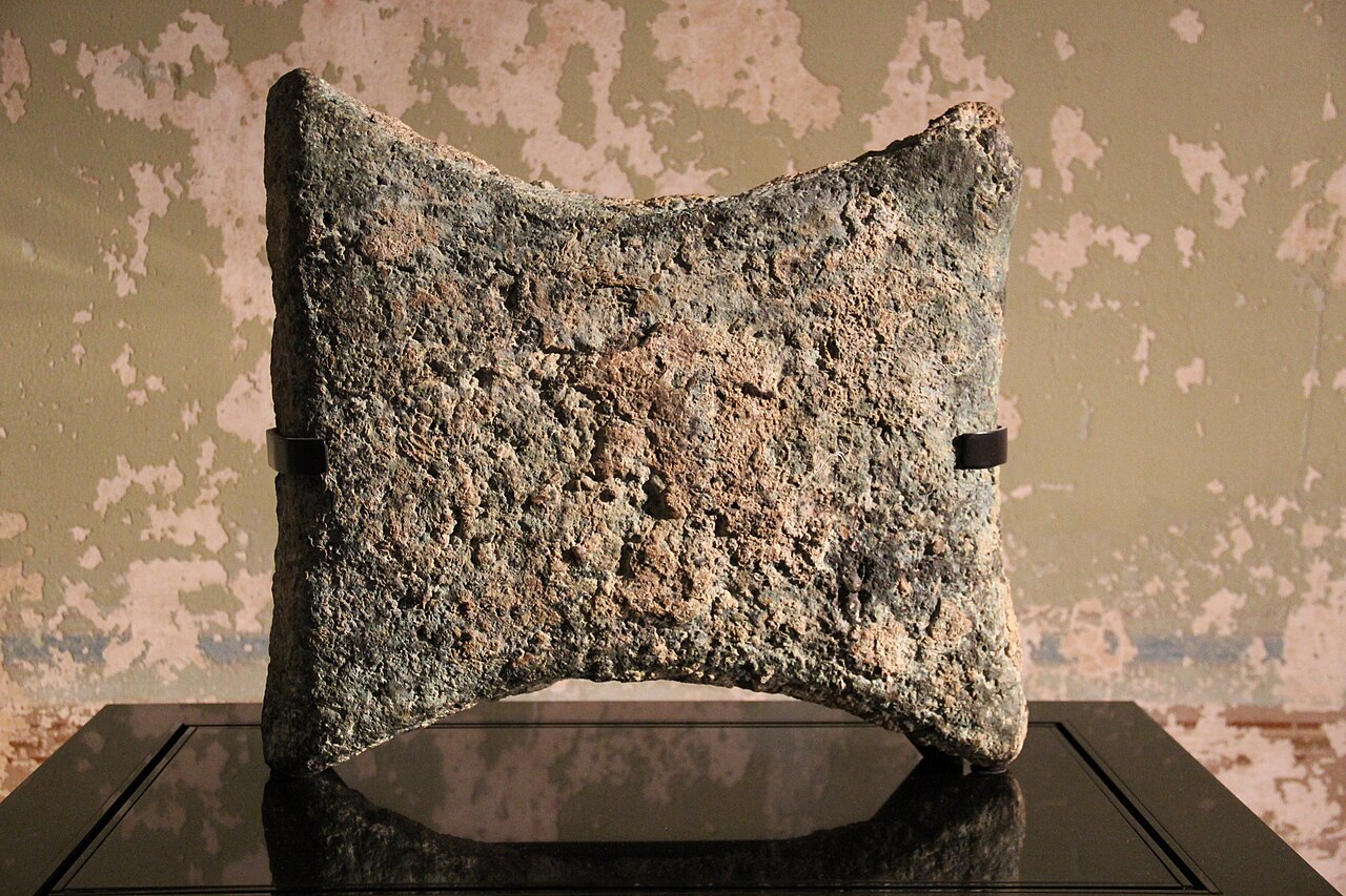 An ancient copper oxhide ingot displayed as a flat rectangular trade object with corner handles.