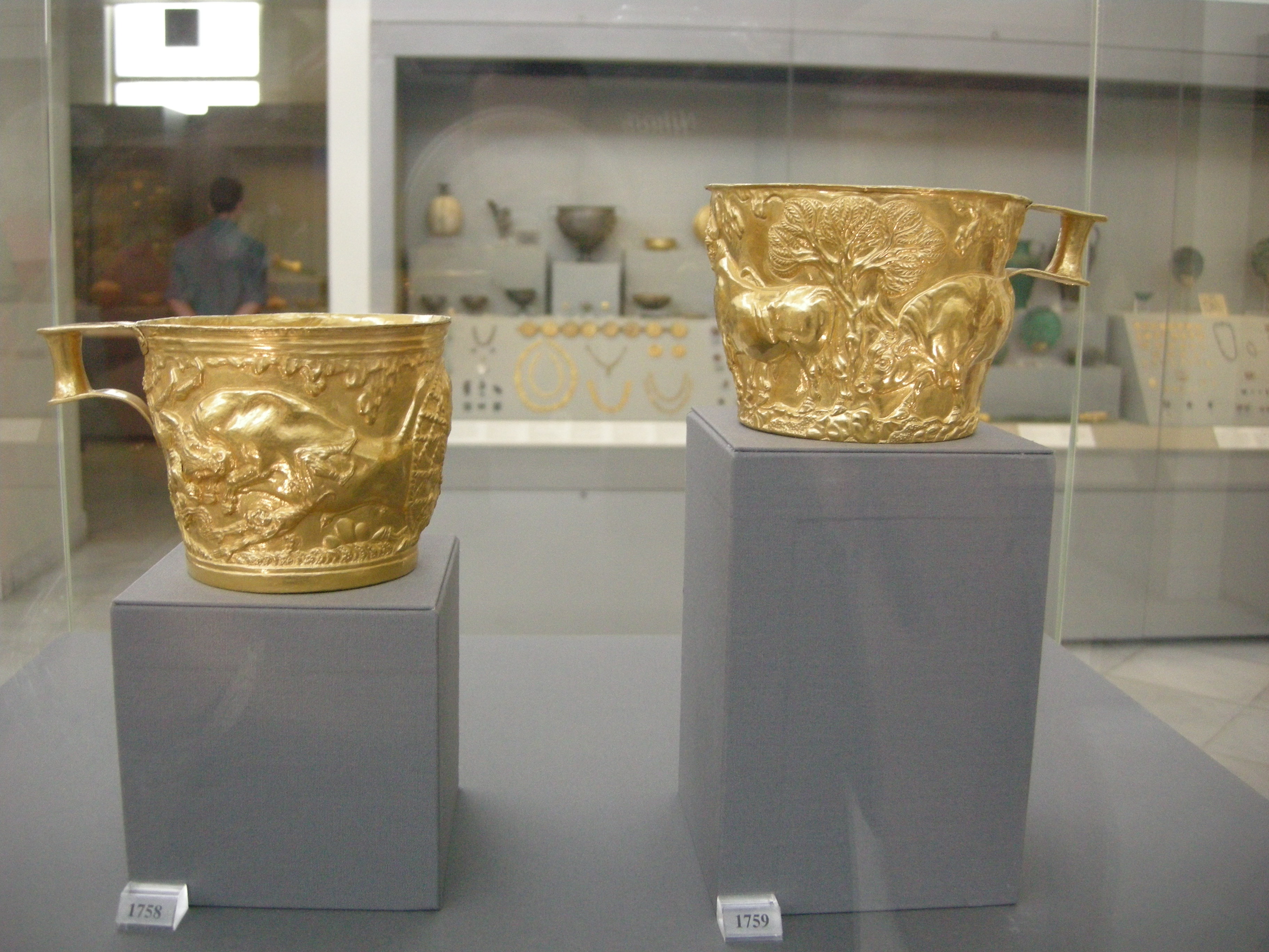 Two ancient gold Vapheio cups displayed in a museum case.